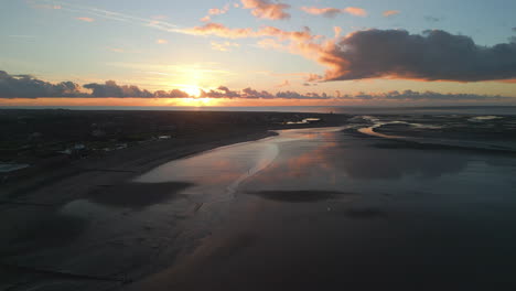 sunset reflections in wet sandy beach with rise up at fleetwood uk