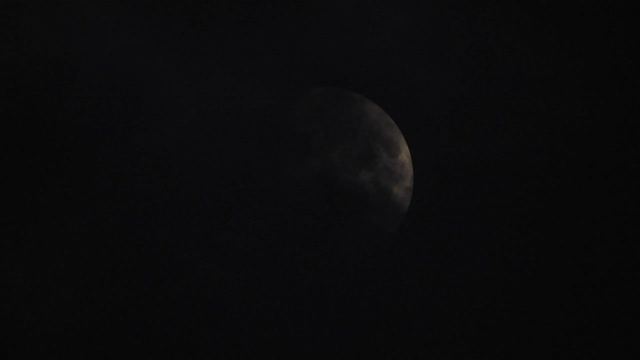 Moon at night with cloud real time. 4k video moon in the black sky.  Clouds passing by moon at night. night sky with cloudy weather