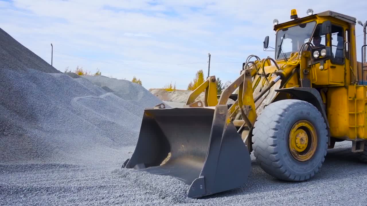 excavadora amarilla cargando grava