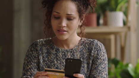 Mujer-Joven-De-Raza-Mixta-Comprando-En-Línea-Usando-Una-Aplicación-De-Comercio-Electrónico-Para-Teléfonos-Inteligentes-Sonriendo-Disfrutando-De-La-Compra-En-Línea-En-Un-Apartamento-Tipo-Loft