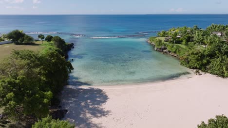pan right aerial shot of white sand caleton beach, dominican republic, with crystal clear waters and bay surrounded by tropical vegetation. coral reef, no waves, snorkeling hot spot