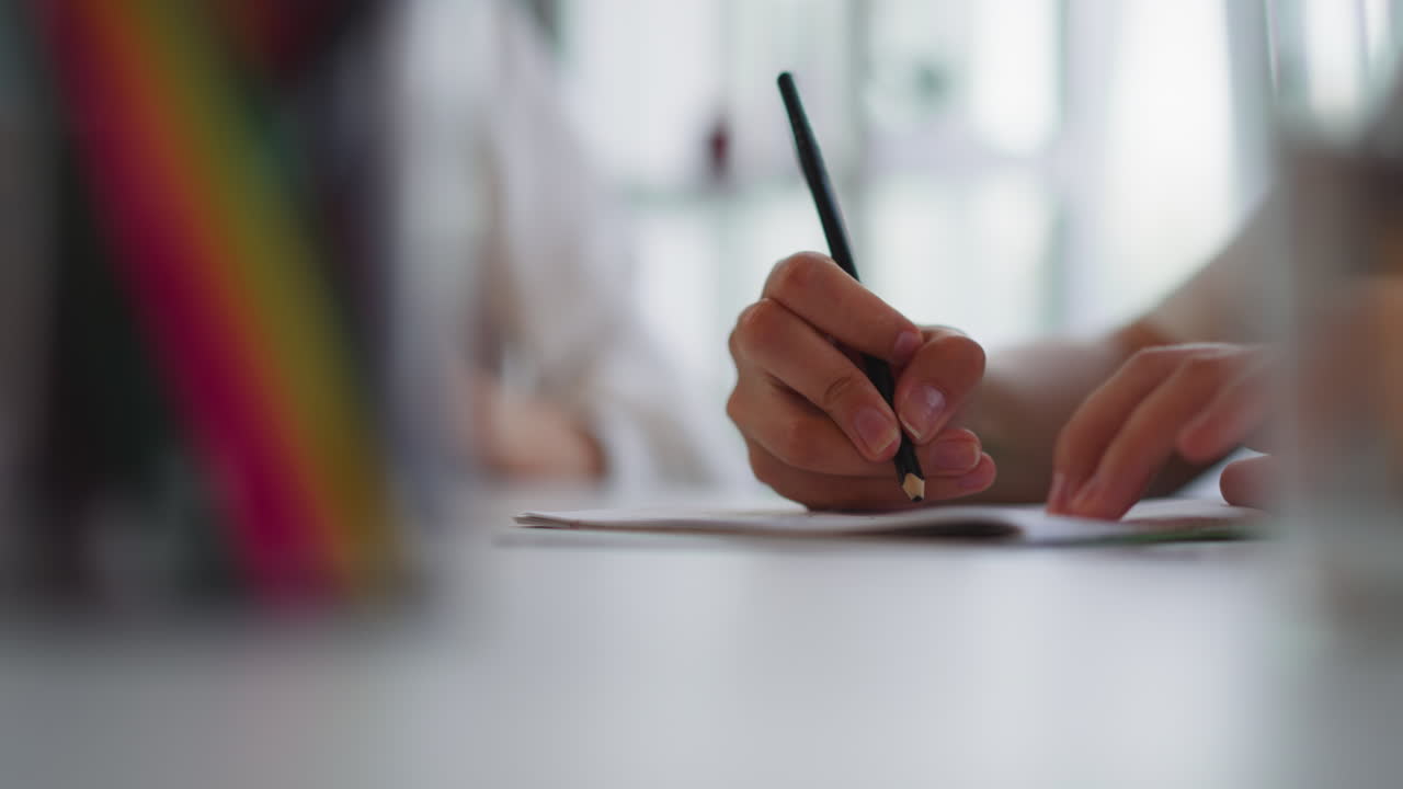 Hands of woman drawing with black pencil in exercise book