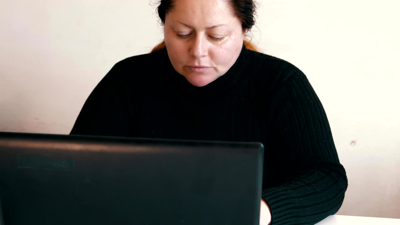 mujer gorda trabajando en una computadora portátil en casa