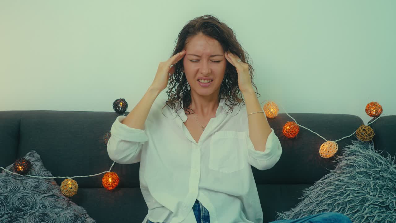 Woman experiencing headache on couch