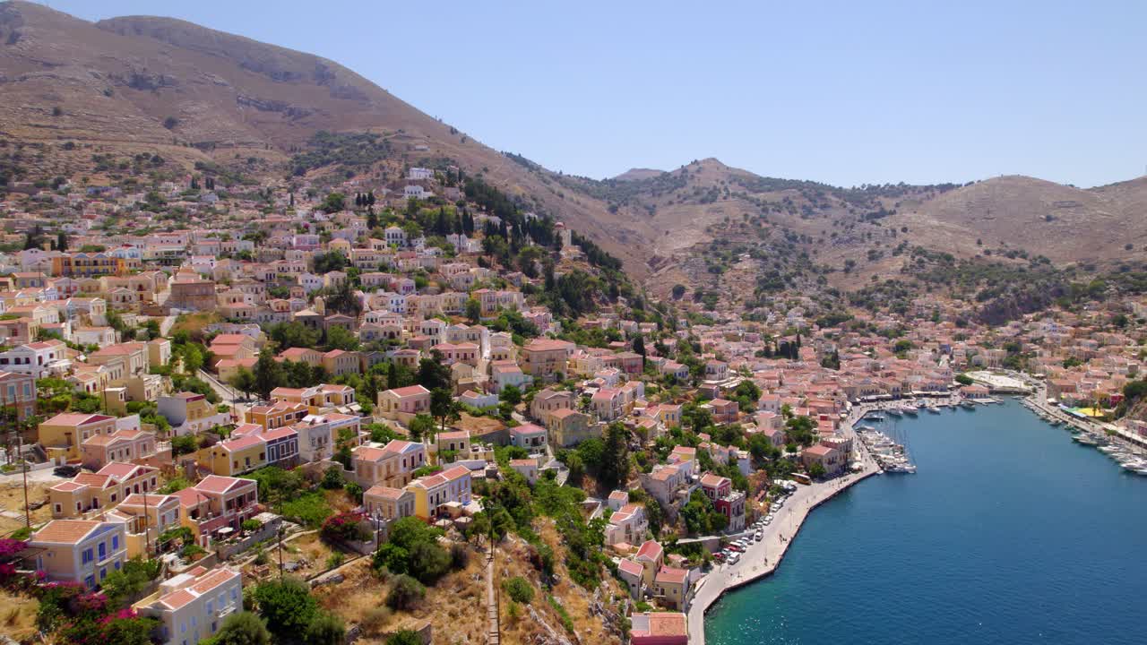 Aerial view of Symi Island’s colorful houses with mountains in the background in Greece