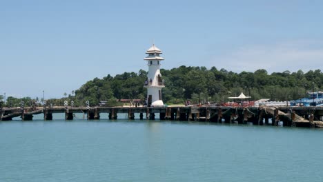 view of white lighthouse and pier from the sea, sliding shot