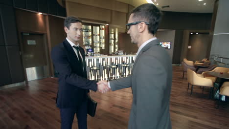 Two-Businessmen-Greeting-Each-Other-In-A-Hotel-Bar