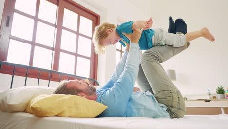 father and son playing on a bed