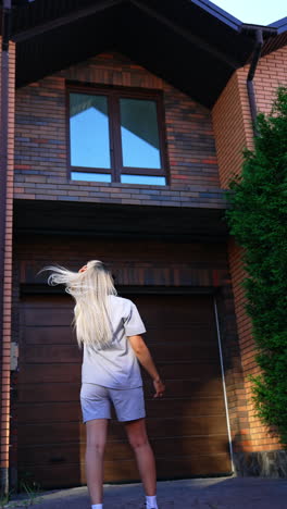 girl admires house at sunset. a young girl with long blonde hair admires a contemporary house in the evening light