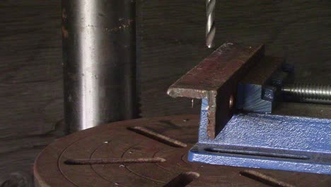 slow motion - drill press starting and beginning to cut into a piece of steel angle iron