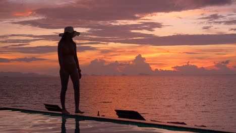 silueta de mujer caminando junto a la piscina con fondo crepuscular