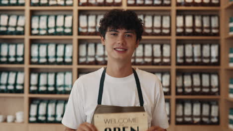 shop owner holding an open sign in a cafe