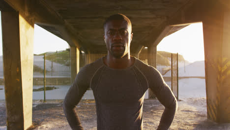 portrait of focused african american man looking at camera, exercising outdoors in the evening