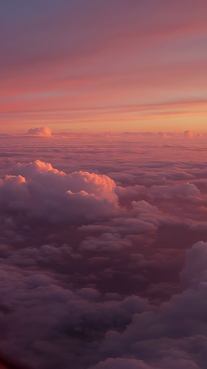 Vertical video: Filming camera catching clouds moving at sunset outside plane window, trim