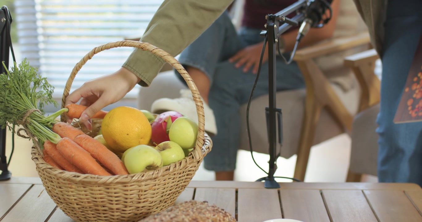 Dopo aver indugiato, donne asiatiche e afroamericane chinate sul tavolo, che prendono una carota dal cesto per il microfono.