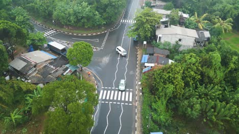 aerial drone view, follow shot of a white car in road with trees in sri lanka