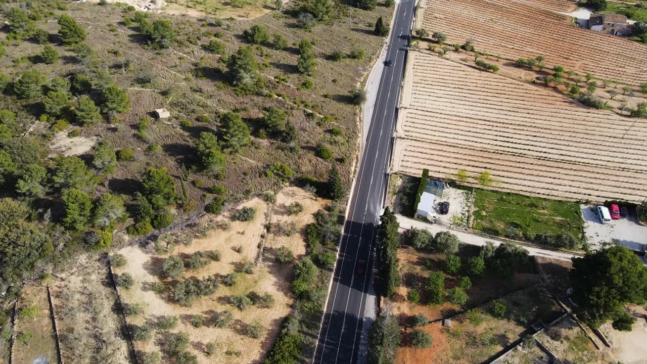 un coche conduciendo a través de un paisaje rural con campos y árboles en un día soleado, vista aérea