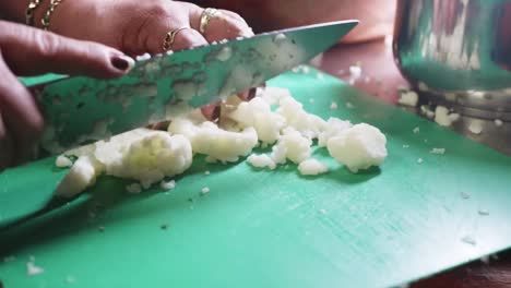 mano femenina cortando coliflor en una tabla de cortar verde con un cuchillo de cocina en un restaurante mexicano de comida sana