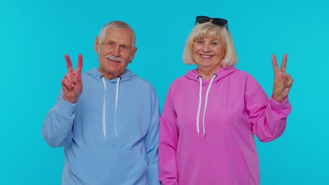 una pareja de ancianos feliz mostrando el signo de la paz.