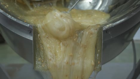 primer plano de la masa caliente y pegajosa de delicias turcas con almendras a medida que se extrae en la bandeja de forma