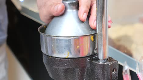 close-up of a hand squeezing an orange in a manual juicer