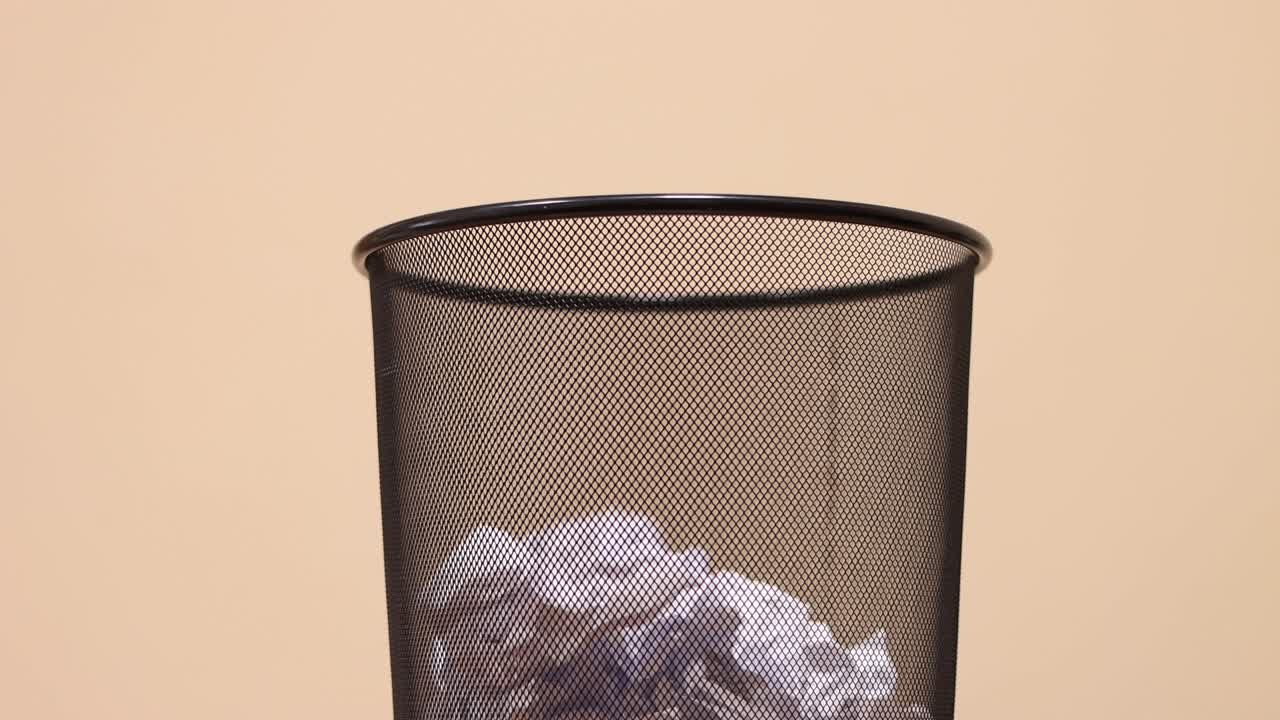 tirando papel arrugado en el contenedor de basura.