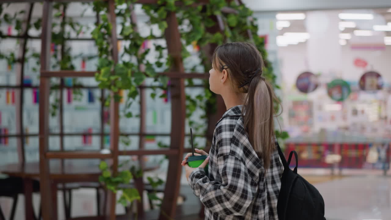 젊은 소녀가 주스를 들고 아름다운 장식 된 실내 공간에서 고 앉아 있으며 부드러운 배경 조명과 현대적인 미학적 세부 사항을 특징으로합니다.