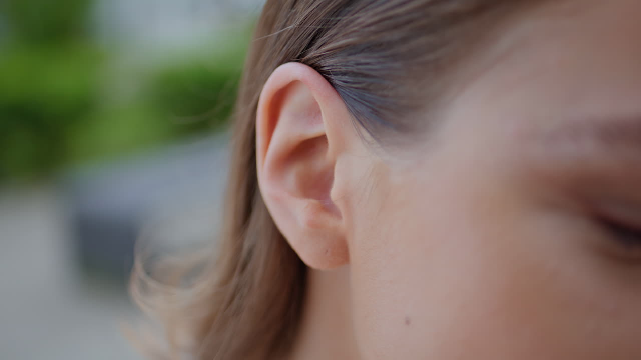 Woman hand fixing hair behind ear playfully at street closeup. Girl hairstyle