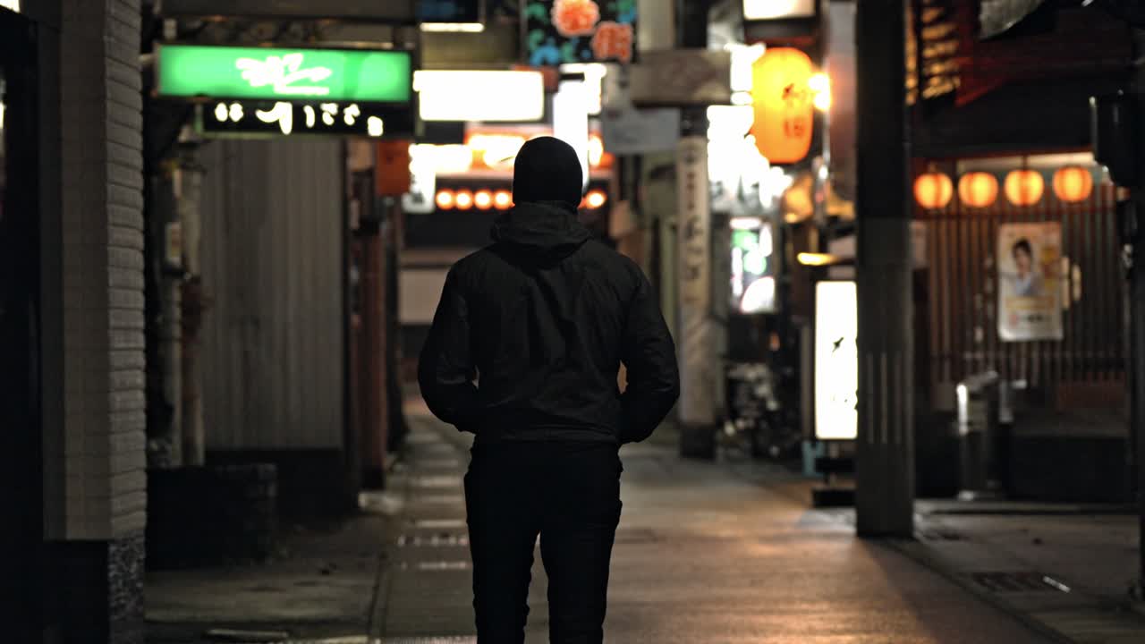 A lone man walks through the quiet streets of Takayama’s historic district at night.
