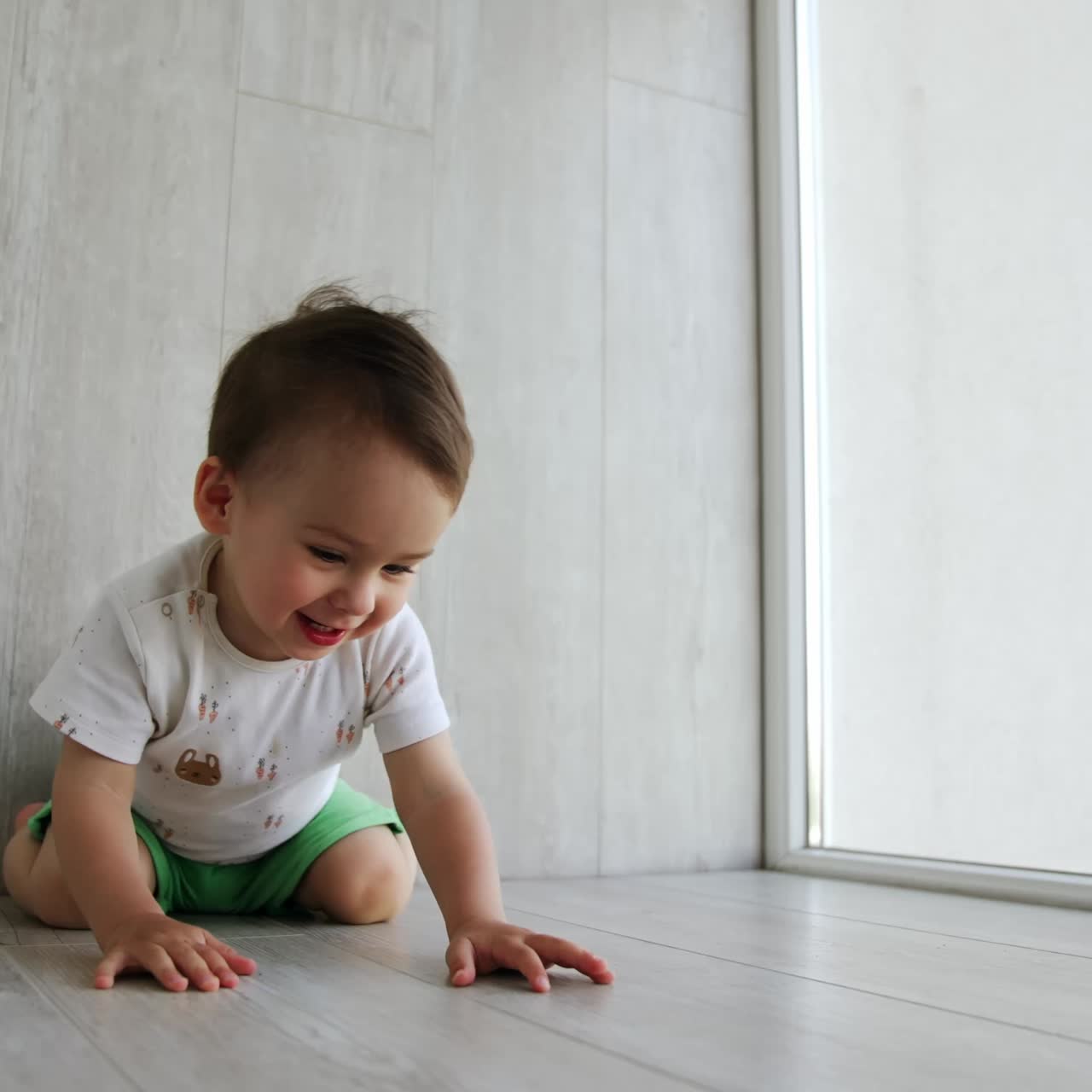 Little toddler boy having fun time at home. Kid sits on the floor and then crawls to the electric socket on the wall