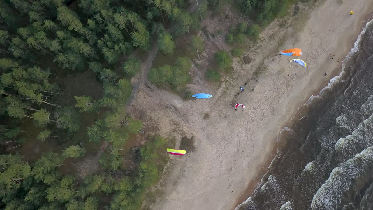 grupo de parapente deslizándose lentamente en la playa usando el poder de la brisa terrestre