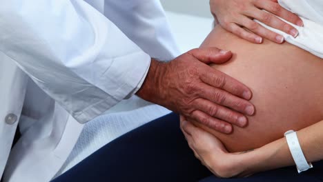 sección media del médico tocando el vientre de las mujeres embarazadas en la sala