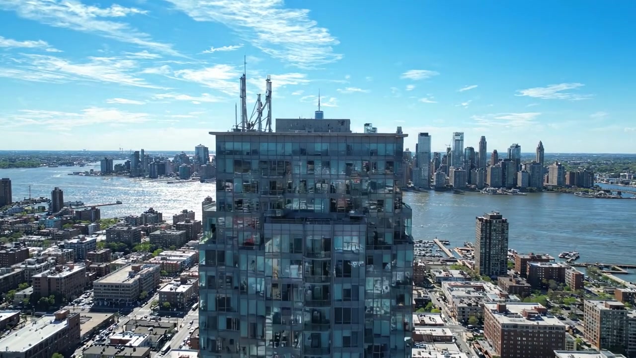 Vista aerea di un paesaggio urbano iconico che si affaccia su un fiume con edifici moderni e cielo blu, catturando il panorama urbano alla luce del giorno