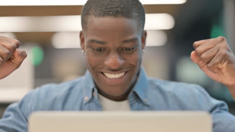 portrait of successful african american man celebrating on laptop
