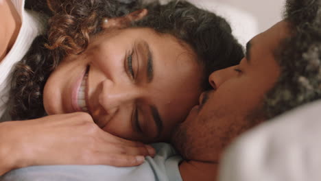 happy young couple lying on sofa embracing sharing romantic relationship enjoying intimacy together at home