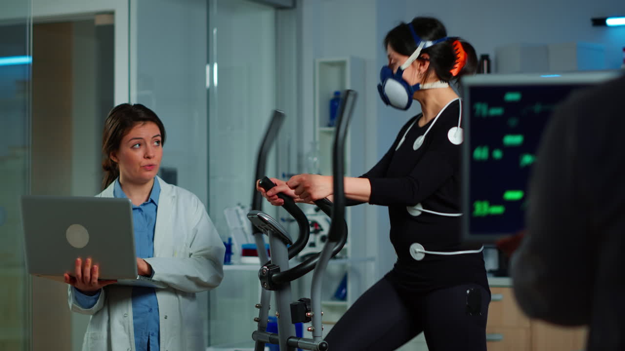 의료 연구원은 스포츠맨의 체력을 측정하는 동안 노트북을 사용합니다.