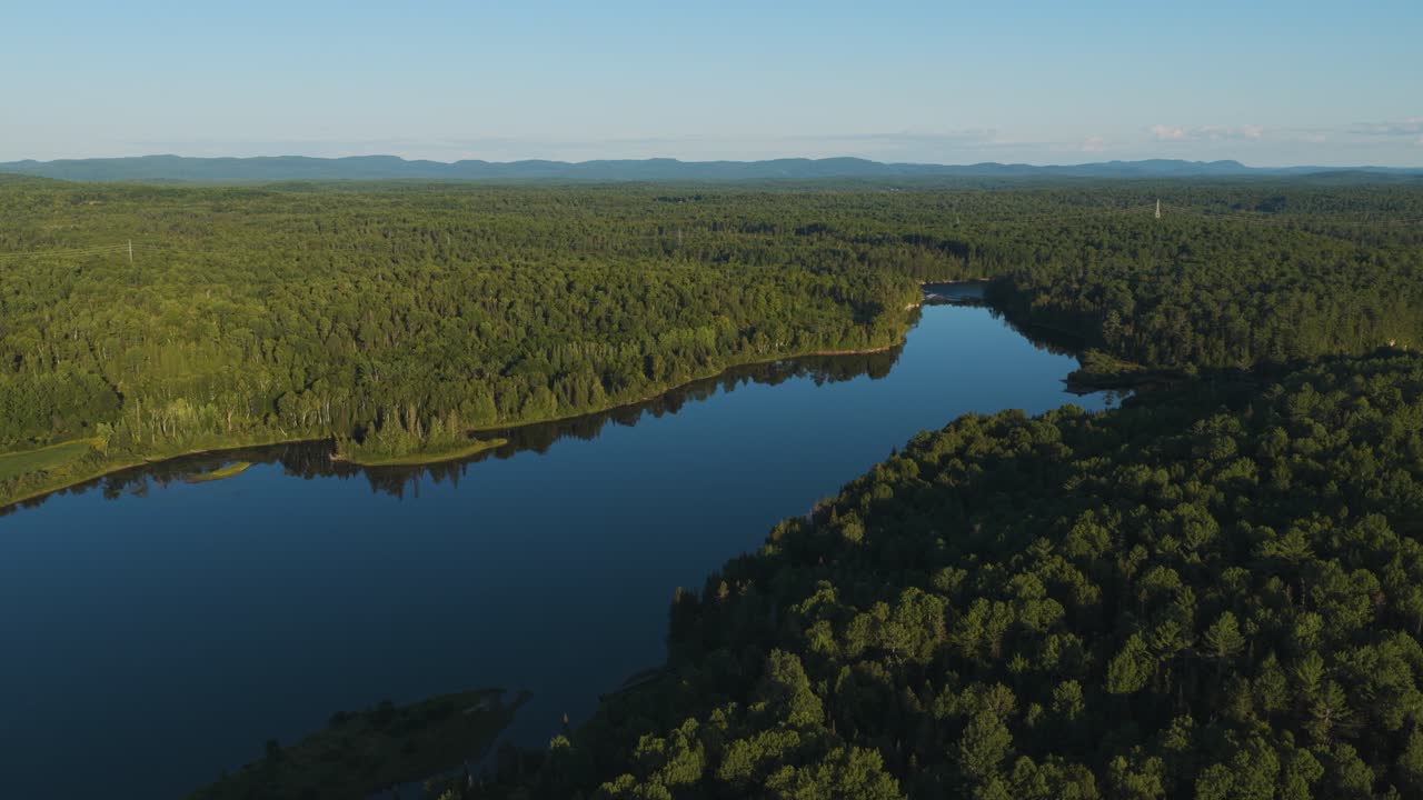 A bird's-eye view of a wooded Canadian landscape with a large, gently flowing river in the middle