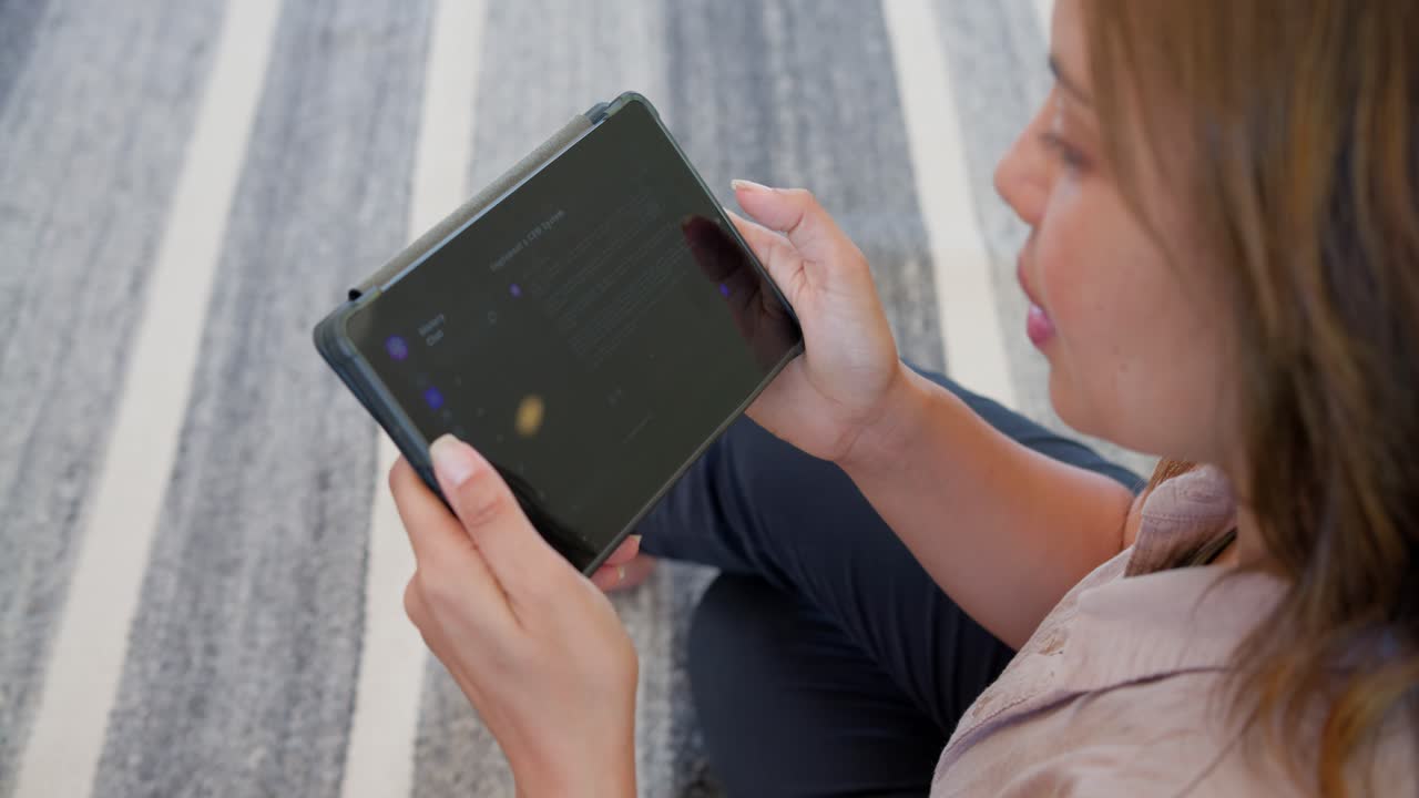 African American woman holding tablet on striped rug, tapping left screen, reading, copy space