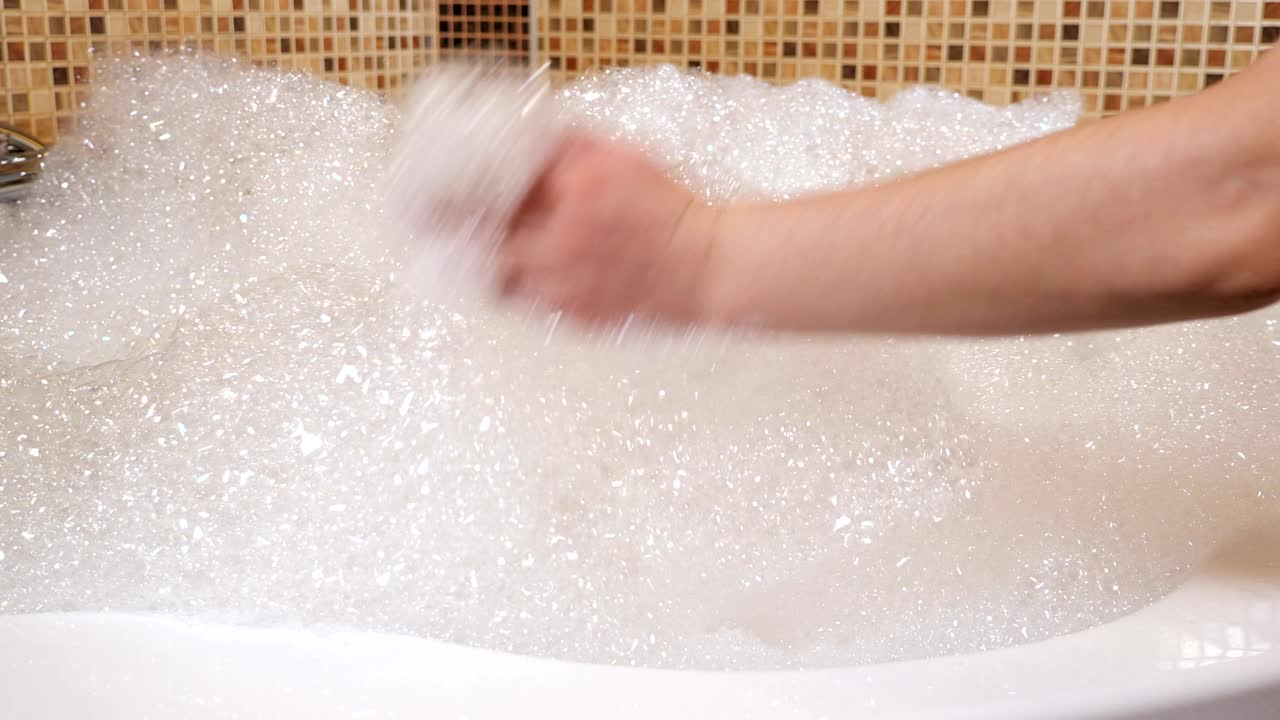 핫에 많은 거품이 있습니다. 여자의 손이 거품을 만집니다.