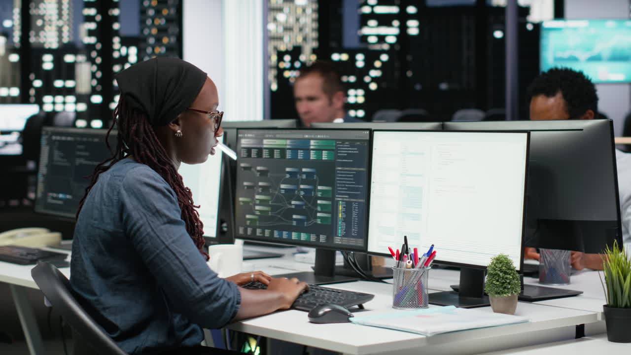 African American Woman Programmer Working on Multiple Computer Screens