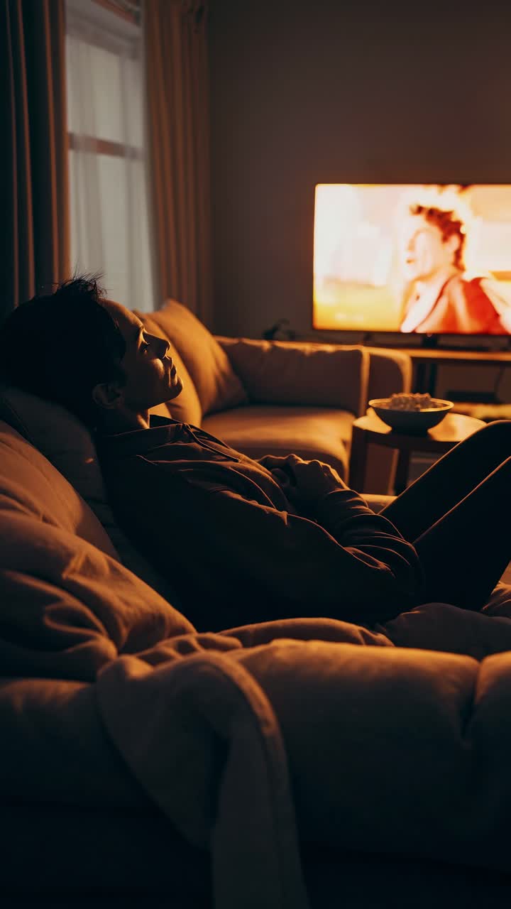 A cozy living room scene with a person relaxing on a sofa, watching a video