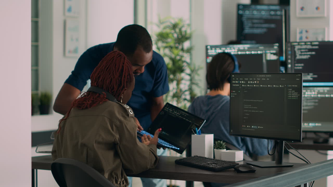 Database developer explaining algorithm to colleague coder pointing at running code