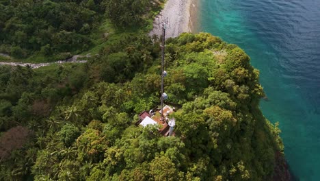 communication tower on top of the hill with lush forested area near beach