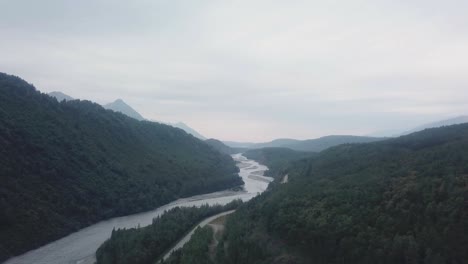 Aerial-view,-drone-flight-along-the-Glenn-Highway-and-the-Matanuska-River-in-the-Chugach-Mountain-Range-of-central-Alaska-on-a-cloudy-summer-day