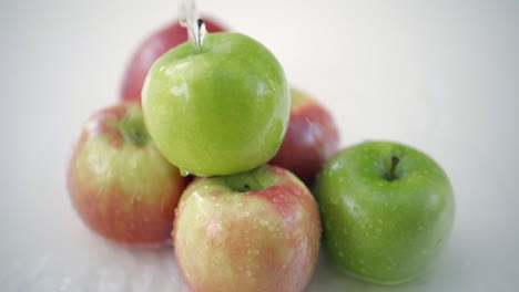 slomo of water poured on apples on white backdrop