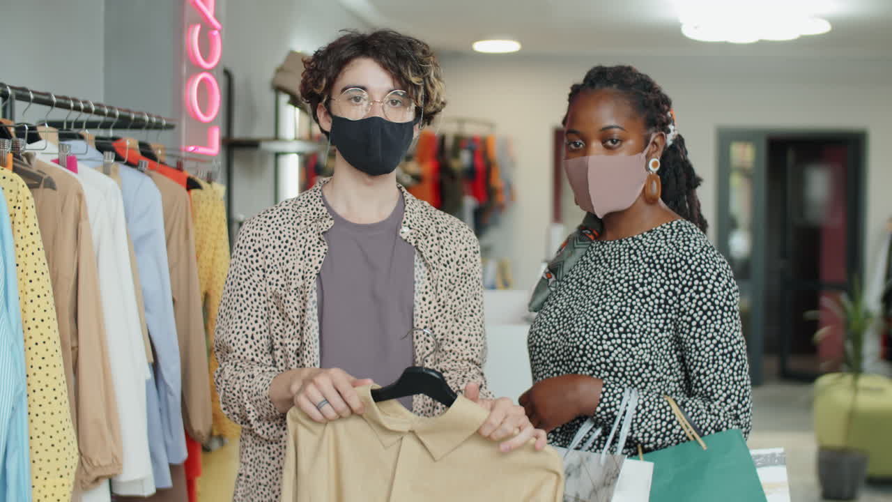 retrato de un hombre y una mujer enmascarados multiétnicos en una tienda de ropa