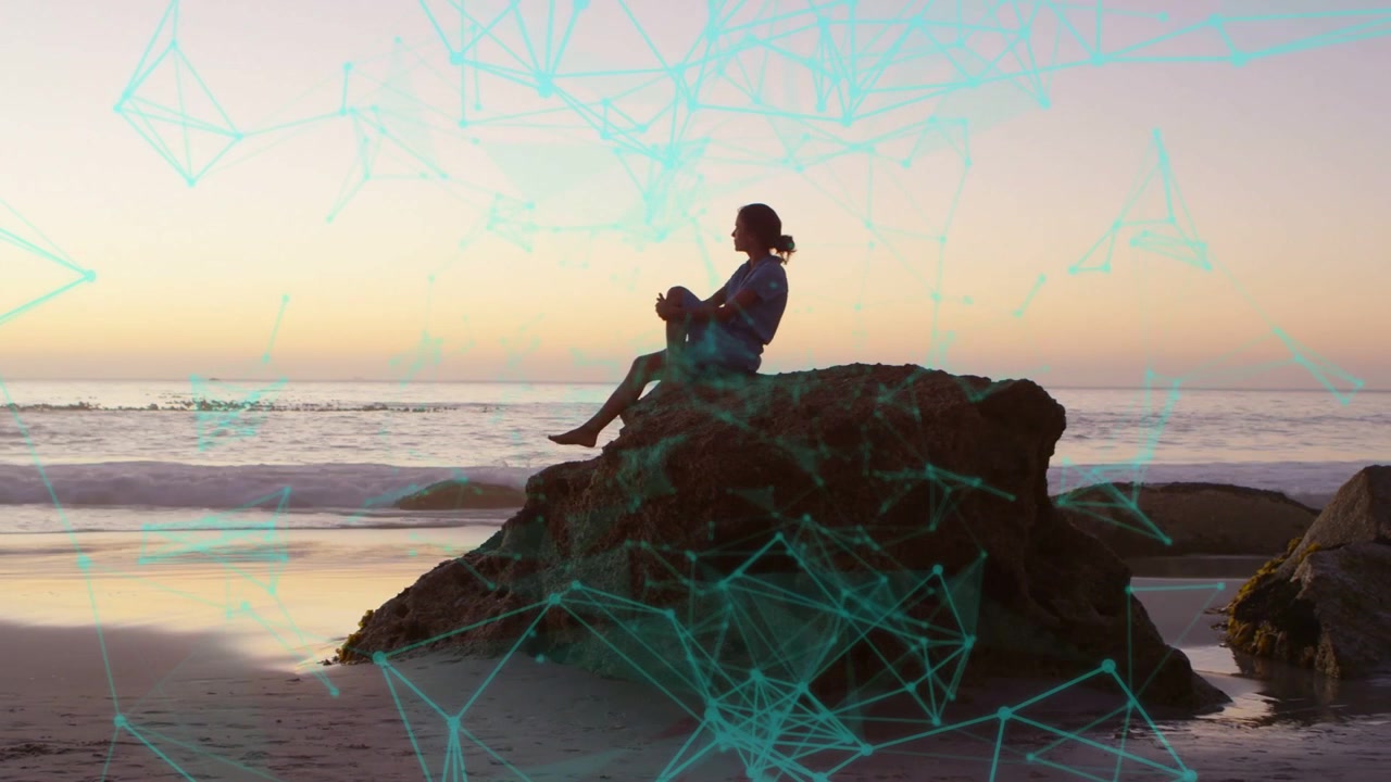 Woman stepping down beach rock into sitting, watching ocean while teal overlay signaling technology