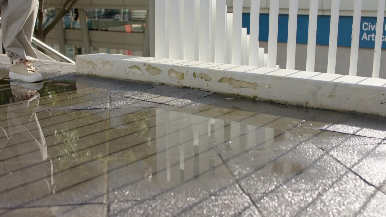 Une femme en baskets marche dans une flaque d'eau, puis une deuxième femme éclabousse sur la terrasse près de la balustrade, avec espace pour texte.