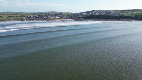 Toma-Aérea-De-Establecimiento-De-Surfistas-Esperando-Las-Olas-En-La-Playa-De-Lahinch