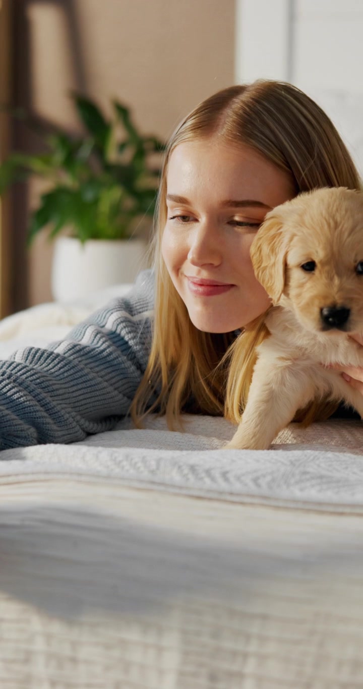 Young Woman Taking Selfie with Golden Retriever Puppy on Bed